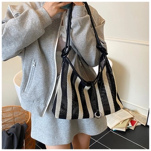 Detail of black and white striped mesh bucket bag with metal ring and tie closure