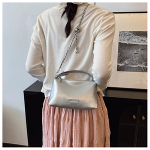 Detailed macro of silver metallic crossbody bag with chain strap and sphere buckle