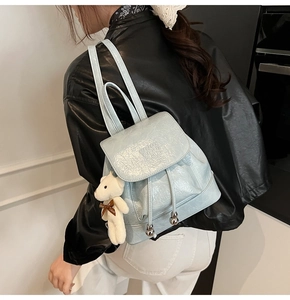 Detail of light blue mini bucket backpack with plush bear charm and metallic drawstring
