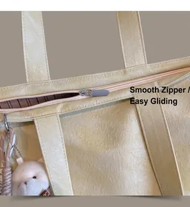 Detail of smooth metal zipper and lychee grain leather on beige tote bag