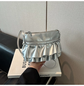 Detail of silver metallic ruffle handbag showing layered texture and zip closure