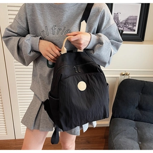 Close-up of lightweight black nylon backpack with cream leather handle on model back