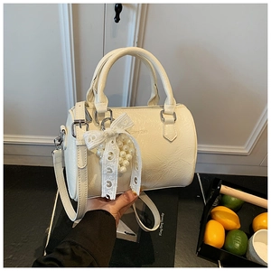 Détail du sac cylindre beige avec breloque perle et texture en cuir plissé élégant