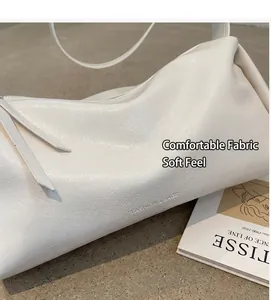 Nahaufnahme der weißen Lederkissen-Tasche mit Fashion & Bags Text auf Holztisch