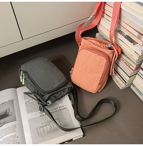 Dual-color nylon crossbody bags in grey and peach shown with books and magazines