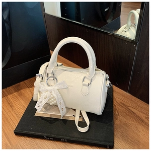 Détail du sac cylindrique blanc avec texture froissée, nœud en dentelle et perle