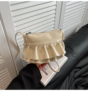 Close-up of cream pleated shoulder bag featuring dual ruffled tiers and smooth PU leather