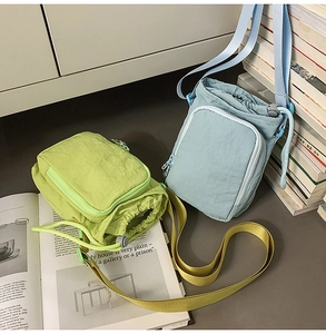 Detail of light green and blue nylon crossbody bags with drawstring and zipper pocket
