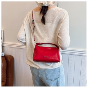 Detail of red quilted leather bag with silver chain strap and top handle on a model