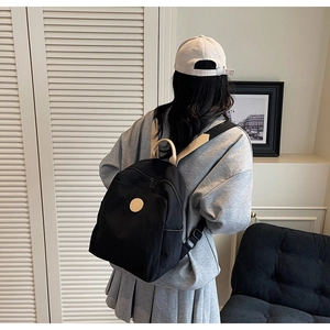 Rear view of a model wearing the lightweight black nylon backpack with a beige leather logo