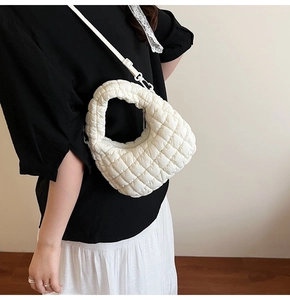 Detailed side view of white quilted dumpling bag worn by model on a minimalist background