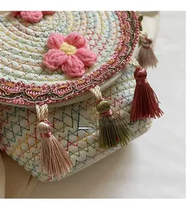 Close-up of handmade woven bucket bag featuring floral lace trim and colorful tassels