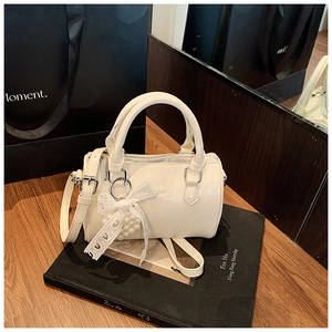 Détail du mini sac cylindre blanc crème avec texture plissée brillante et breloque perle