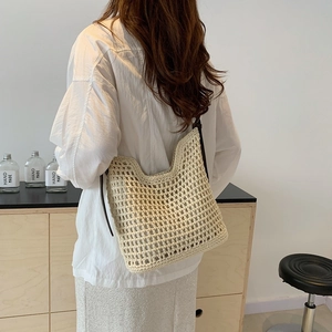 Detail of a beige crochet tote bag with large hollow mesh design and dark leather strap