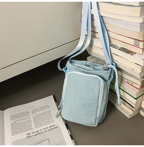 Detail of light blue nylon water bottle crossbody bag with drawstring and zip pocket