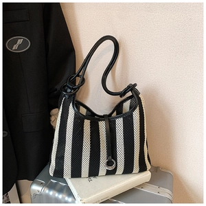 Detail of minimalist black and white striped mesh tote bag with leather strap and metal ring