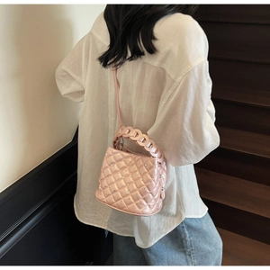 Borsa a secchiello rosa trapuntata con strass e manico intrecciato indossata