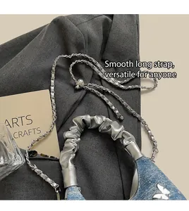 Dettaglio borsa in denim e pelle argento con farfalla metallica e tracolla regolabile