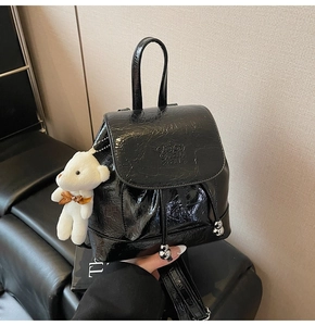 Detail of black glossy pleated backpack with drawstring and plush bear charm