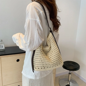 Detail of crochet tote bag with beige woven texture and dark brown leather strap