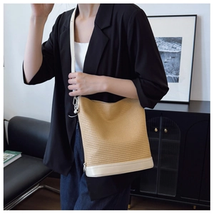 Detail of woven straw shoulder bag featuring a cream leather base and modern metal hardware