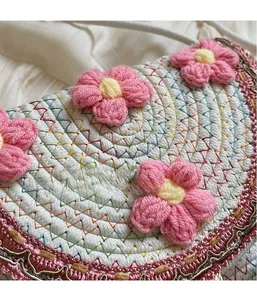 Close-up of hand-woven white bucket bag featuring 3D pink crochet flowers and golden trim