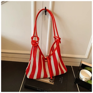 Detail of red and white striped mesh tote bag with metal ring and faux leather strap