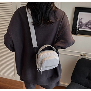 Close-up of lightweight nylon crossbody bag featuring a front zipper pocket and wide strap