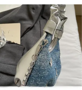 Dettaglio del manico in metallo argento e denim con strass per una borsa a spalla stile Y2K