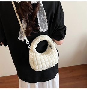 Detailed back view of a white quilted dumpling bag worn as a crossbody with a stylish black outfit