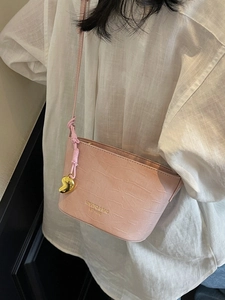 Pink crocodile pattern bucket bag with golden heart charm shown on model shoulder