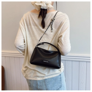 Detailed view of the black leather shoulder bag with a metal chain strap and logo