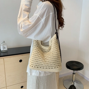 Close-up of beige crochet tote bag with hollow knit design and brown leather straps