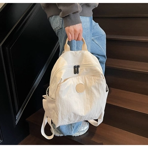 Close-up of lightweight off-white nylon backpack featuring dual zippers and round logo