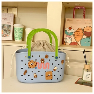 Detail of blue perforated beach tote with green handles and cute cartoon charms