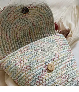 Detail of woven bucket bag featuring rainbow wave stitching and golden magnetic snap closure