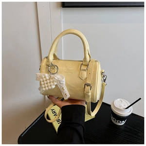 Détail du sac cylindre Boston jaune crème avec texture froissée et breloque nœud perlé