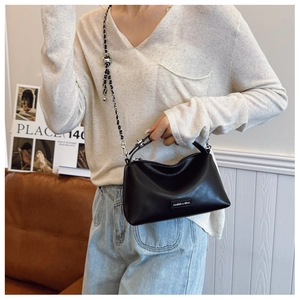 Detail of black leather handbag with chic chain strap and brand metal logo on front