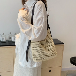 Close-up of cream woven crochet tote bag with dark brown leather straps on a model