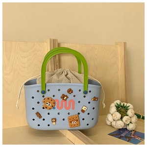 Close-up of blue EVA hollow tote bag with green handles and cartoon decorative charms