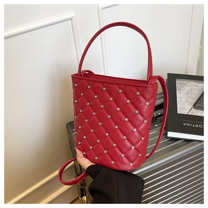Dettaglio della borsa a secchiello rossa trapuntata con strass e texture in pelle lucida
