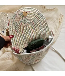 Detail view of woven bucket bag with colorful stitching, tassels, and magnetic closure
