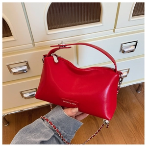 Detailed shot of a red leather tote bag featuring a smooth finish and silver metal chain strap