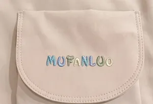 Close-up of colorful MUFANLUO embroidery on pink canvas backpack with durable stitching