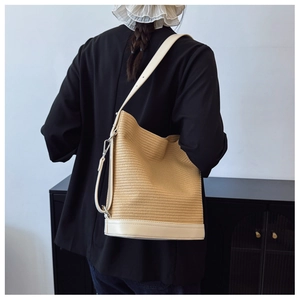 Detail of woven straw bucket bag with cream leather base and adjustable strap