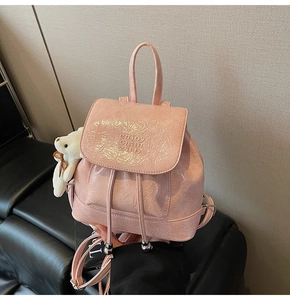 Detailed macro view of pink bucket backpack with enjoy chain logo and bear charm