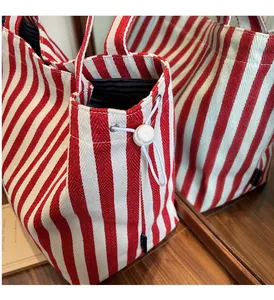 Detail of red and white striped canvas tote bag with durable white drawstring and round buckle