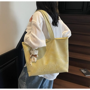 Detail of yellow pebbled leather tote bag with H.SHAN logo and cute white bear charm