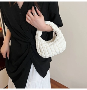 Detail of white quilted cloud bag featuring soft ruched fabric and silver zipper closure
