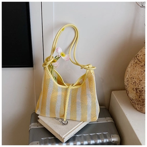 Detail of yellow and white striped mesh hobo bag with silver pendant on a book